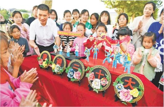 图②：10月13日，郯城县马头镇中心小学，临沂市技师学院教师韩红元向师生们展示面塑作品。（□通讯员房德华报道）