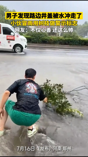 路边井盖被水冲走，小伙冒雨用树枝做警示标志