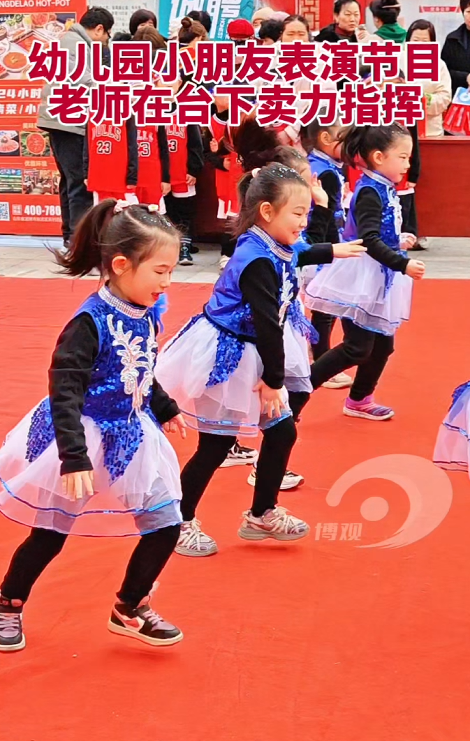 幼儿园小朋友表演节目，老师在台下卖力指挥