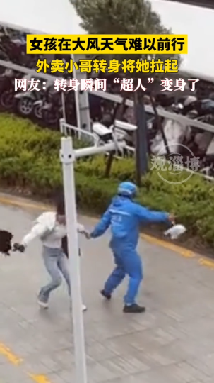 女孩在大风天气难以前行，外卖小哥转身将她拉起