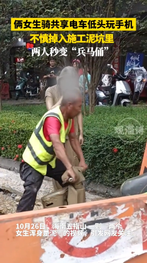 俩女生骑共享单车低头玩手机，不慎掉入施工泥坑里