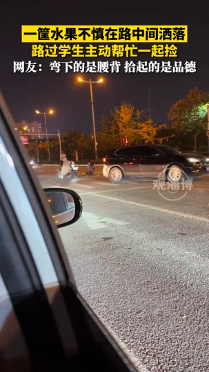 一筐水果不慎在路中间洒落，路过学生主动帮忙一起捡