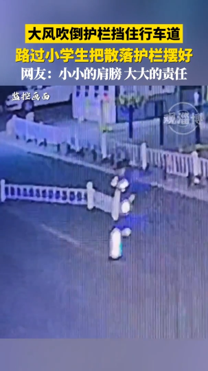 大风吹倒护栏挡住行车道，路过小学生把散落护栏摆好