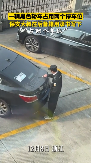 一辆黑色轿车占用两个停车位，保安大叔在后备箱用隶书写下&ldquo;占两个车位&rdquo;