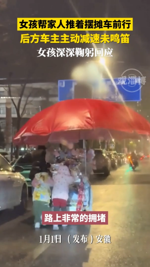 女孩帮家人推着摆摊车前行，后方车主主动减速未鸣笛