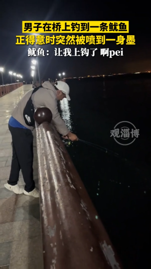 男子在桥上钓到一条鱿鱼，正得意时突然被喷到一身墨
