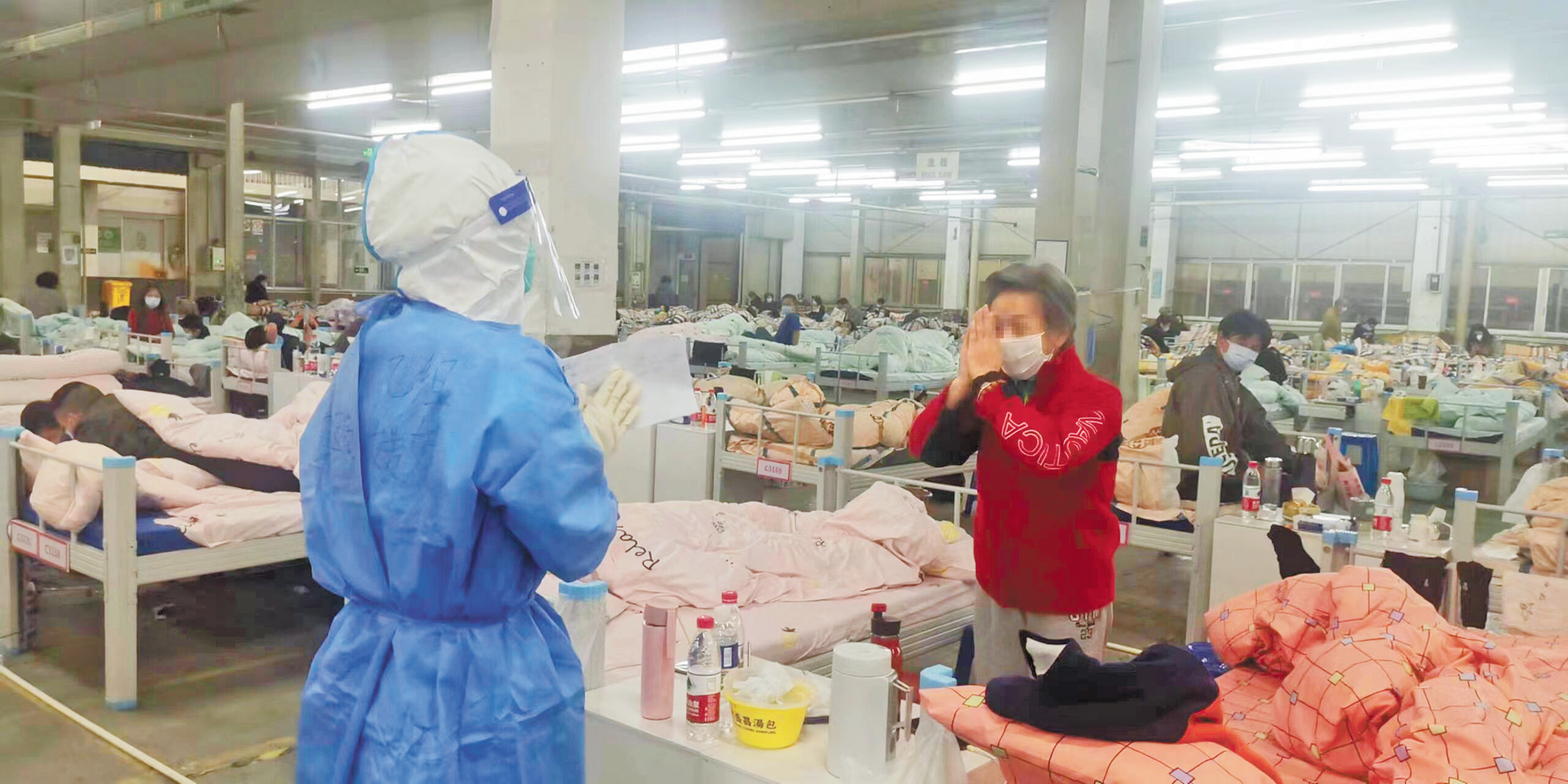 方舱内一位老年患者与队员互相合十致敬